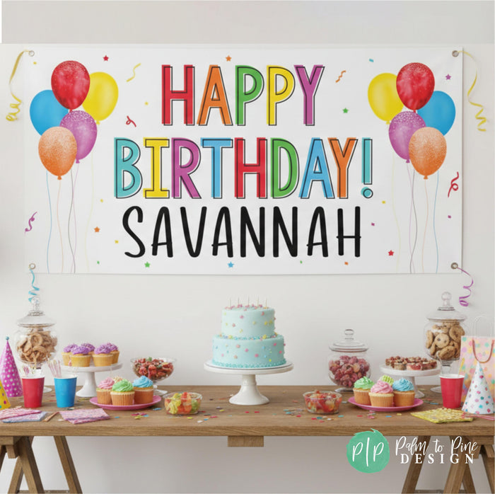A colorful birthday banner with the text "HAPPY BIRTHDAY! SAVANNAH" is displayed on a wall, with a table filled with various desserts, including a cake, cupcakes, and candy.