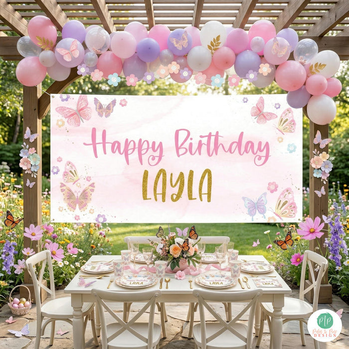 Whimsical pink butterfly birthday banner displayed above a styled table with matching party decorations in backyard garden party