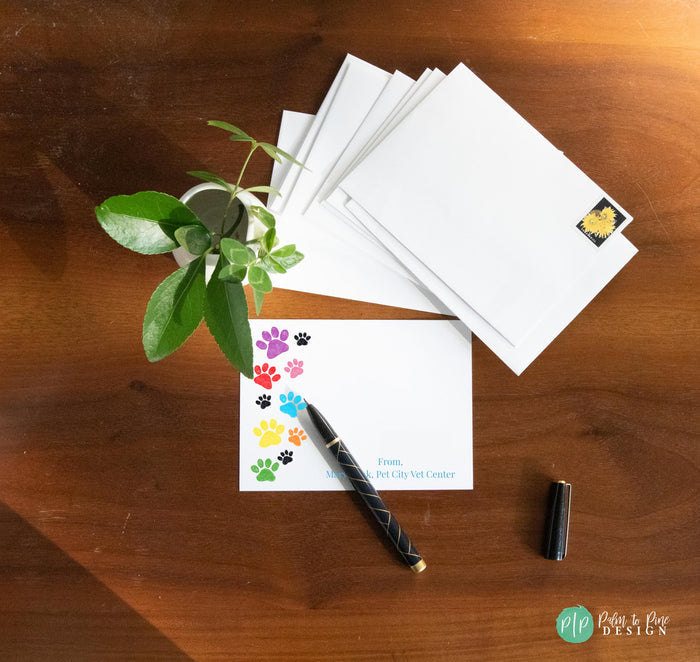 Custom veterinary stationery set with vibrant, colorful text and adorable clipart of cats, dogs, and rainbow paw prints. Includes personalized notepad and note cards, perfect for vet clinics, techs, and animal lovers.