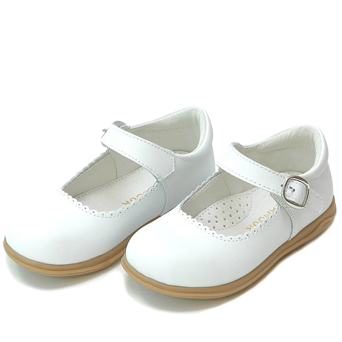 White children's shoes with brown soles on a white background