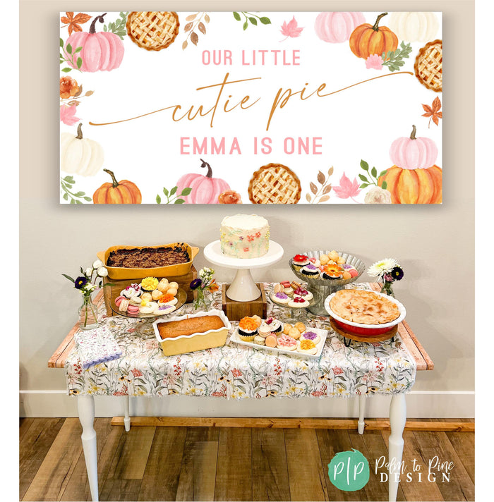 Little Cutie Pie Pumpkin Birthday Banner behind a fall themed dessert table with pies, crisps and floral cupcakes