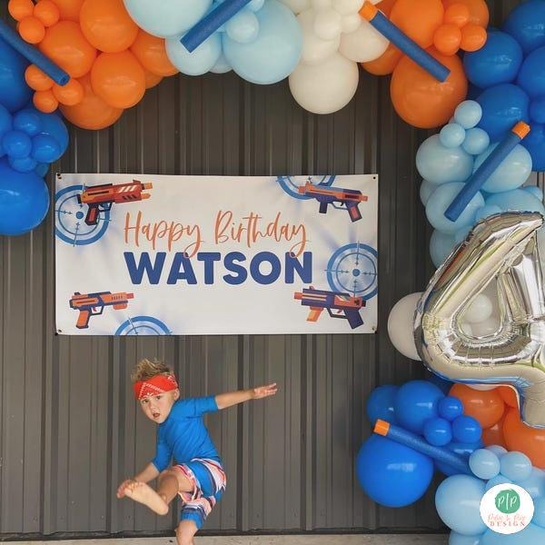 Nerf gun birthday for boys with personalized banner and nerf inspired balloon garland in orange and blue color scheme