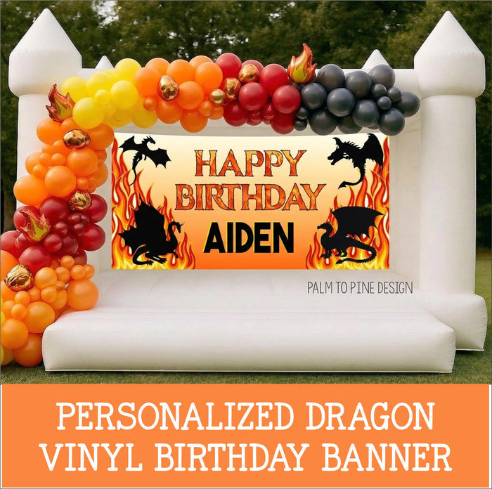 Fire Dragon birthday banner hung on bounce house, surrounded by red, orange and black balloon garland