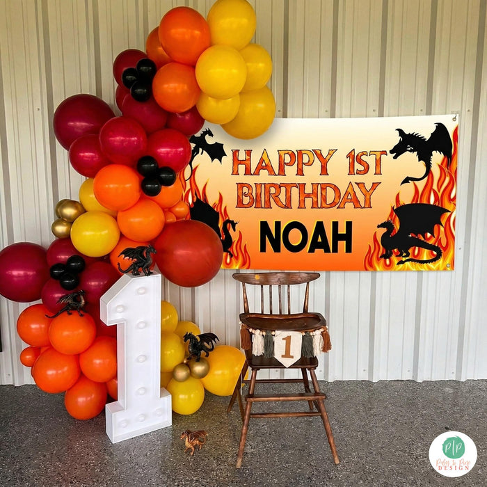 First Birthday Highchair photo with fire dragon theme. Set up includes personalized birthday banner, large balloon garland and marquee light number one