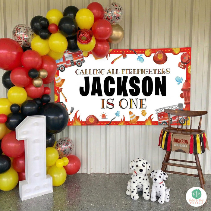 Boys first birthday highchair photo in firefighter theme with personalized banner, balloon garland and dalmatian stuffed animals