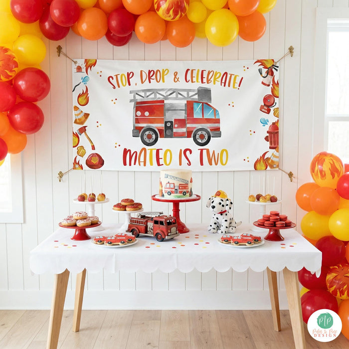 firefighter birthday party with personalized kids banner and modern dessert table, surrounded by red, orange and yellow balloon garland