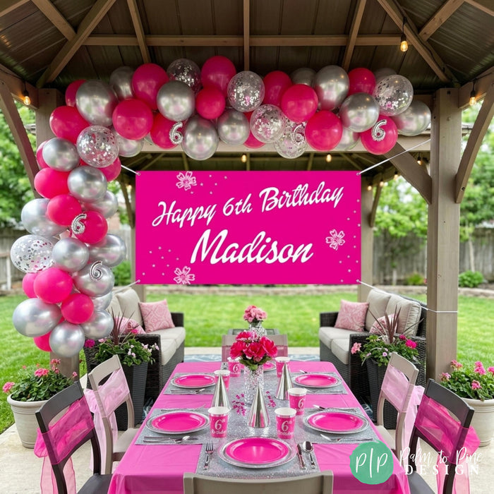 Girls backyard birthday setting in a hot pink and silver metallic color scheme with personalized banner, balloon garland and table setting.