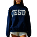 A woman wearing a navy blue pullover hoodie with 'JESUS' printed in large white block letters across the chest, paired with light gray shorts, set against a rustic wooden background.