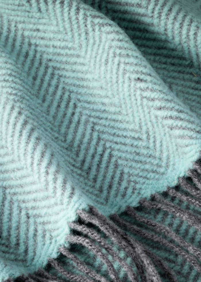 Close-up of a teal and gray herringbone patterned scarf with fringes.