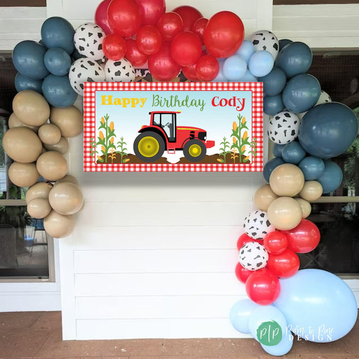 tractor birthday party with red gingham background and stalks of corn or wheat for farmers birthday party surrounded by balloon garland