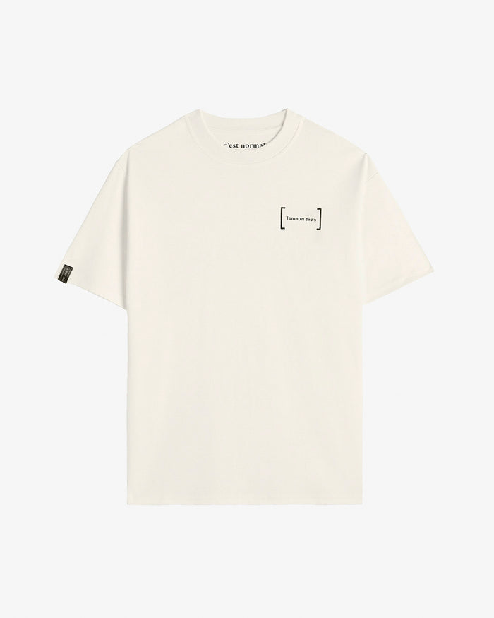 A front view of Le T-Shirt in cream, laid flat on a white background. The image highlights the high ribbed collar, oversized fit, the black mirror c'est normal logo on the chest, and the black satin cuff tag on the sleeve.