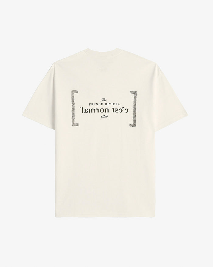 A back view of Le T-Shirt in cream, laid flat against a white background. The image highlights the black printed graphic on the back featuring the FRC Edition mirror logo and "c'est normal".