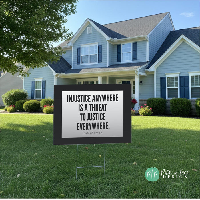 a anti ice yard sign with the text "INJUSTICE ANYWHERE IS A THREAT TO JUSTICE EVERYWHERE" in a grassy yard in front of a house.
