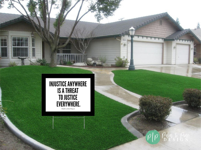 a social justice sign in front of a house with a Martin Luther King Jr. quote about justice, surrounded by a well-maintained lawn and landscaping.