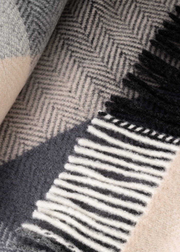 Close-up of a textured fabric with a herringbone pattern and fringed edge.
