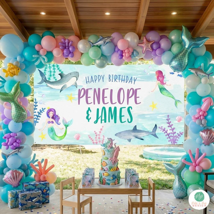 Watercolor mermaid and shark birthday party set up with ocean animals and coral outdoor birthday party.