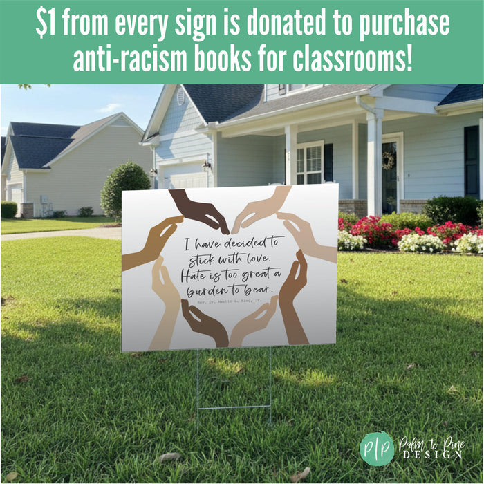 a sign that reads "I have decided to stick with love. Hate is too great a burden to bear." The sign is placed in front of a house with a lawn and flowers. There is a message about donating anti-racism books to classrooms with each purchase