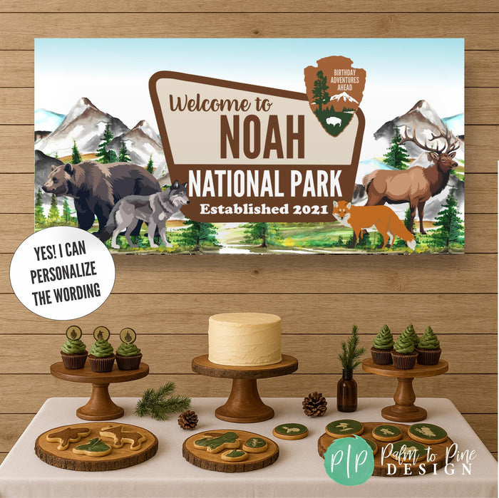 National park themed birthday banner with mountains and wildlife styled behind a dessert table at a boys birthday party