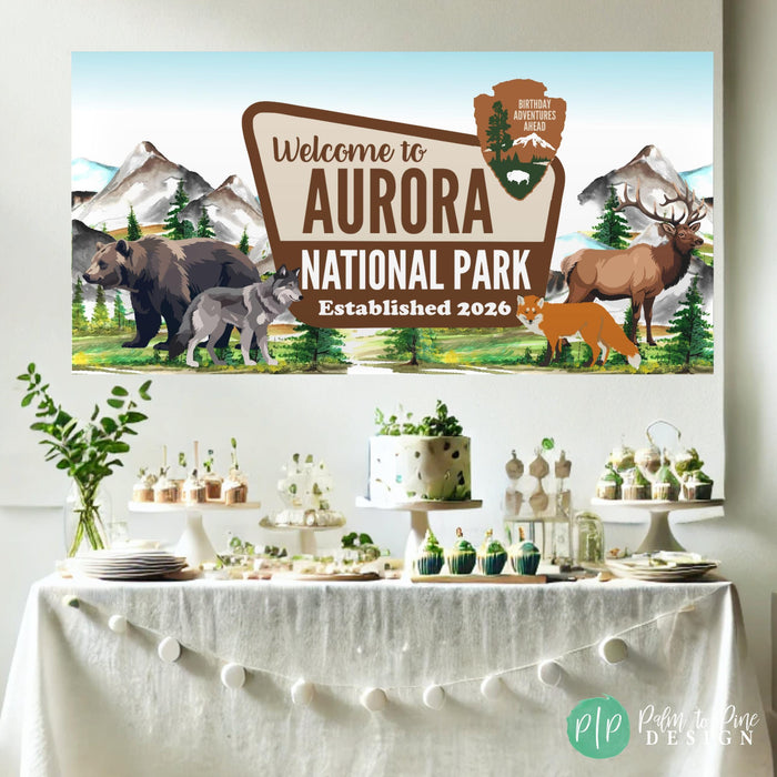 National park themed birthday banner with mountains and wildlife styled behind a dessert table at a girls birthday party