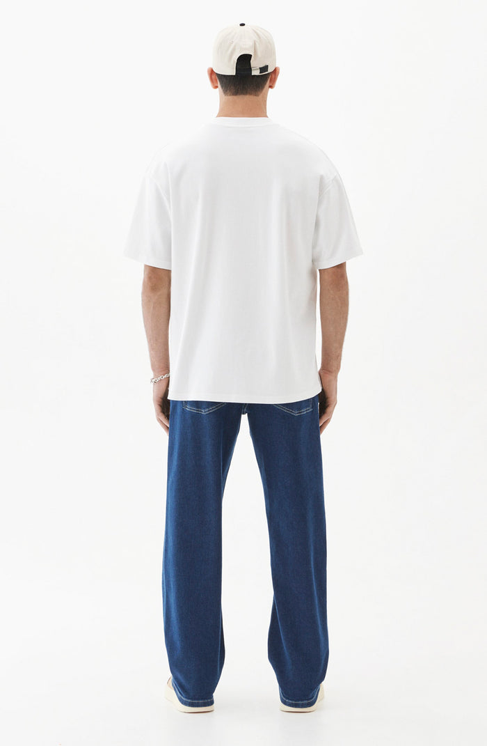 A back view of a man wearing the Oversized Tonal T-Shirt in white, paired with blue jeans and a light-colored cap, standing against a white background.