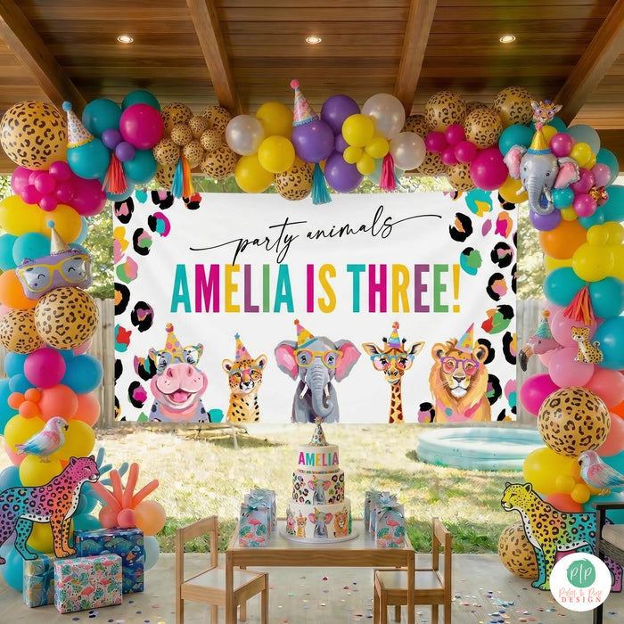 Vibrant Party Animal Jungle birthday party set up with large personalized banner and cheetah print balloon garland, set outdoors on covered patio