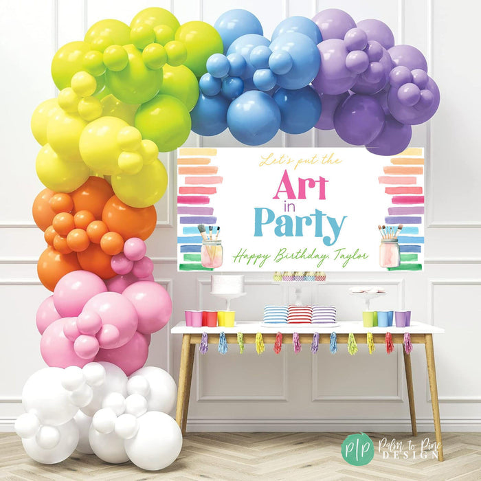 bright rainbow girls birthday backdrop for art birthday party with personalized "Art in Party" birthday banner and rainbow balloon garland