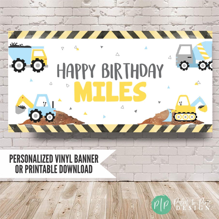Boys construction birthday banner in light yellow and blue pastel color scheme, design includes various construction vehicles like excavator, dump truck and bulldozer