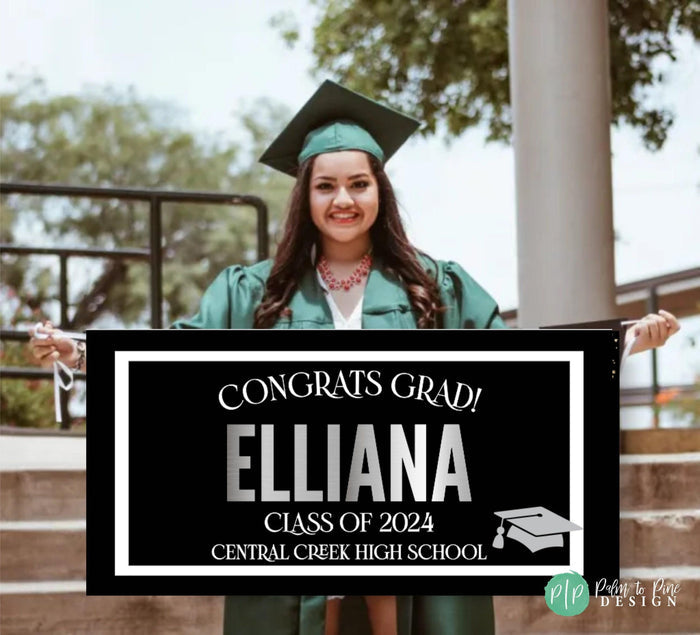 A black and white graduation sign with the text 'Congrats Grad! Grads Name, class of 2025 and grads High School' in silver lettering. A silver graduation cap icon is in the bottom right corner.