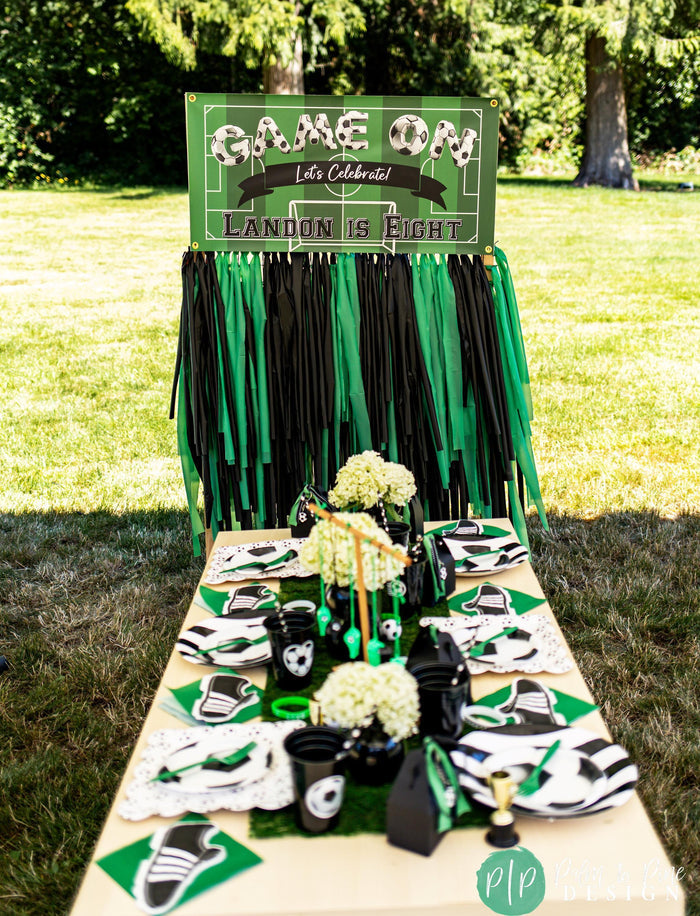 Modern boys soccer birthday party in green and black with soccer table place settings and personalized banner