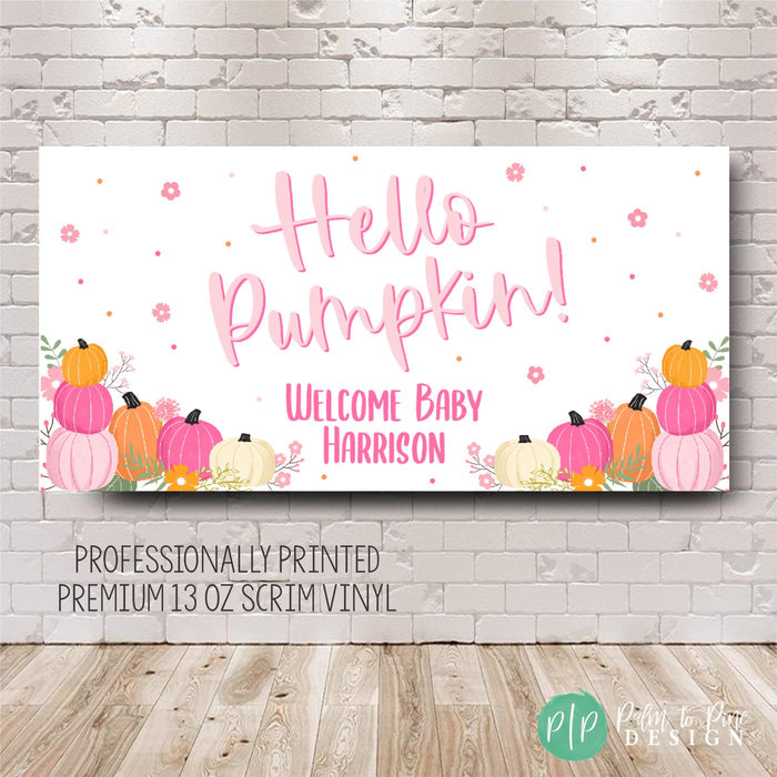 Pink and white baby shower banner featuring the text 'Hello Pumpkin!' and 'Welcome Baby Harrison'. The design includes pink and orange pumpkins with floral accents.  Professionally printed on premium 13oz scrim vinyl.  Perfect for fall baby shower decorations.