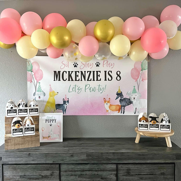 Puppy Birthday Party in Pink and Gold with adopt a puppy stuffies and a personalized birthday banner featuring dogs in party hats and balloons
