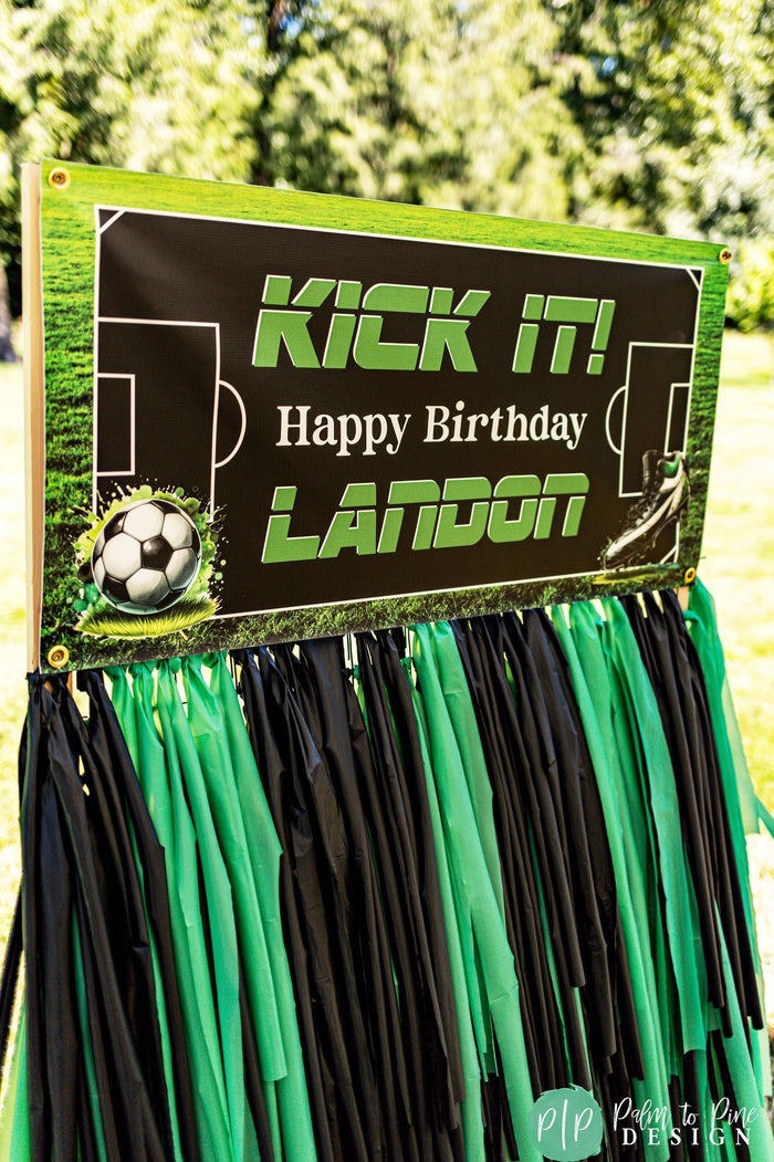 Kick It soccer themed birthday banner with soccer field backdrop, soccer ball and cleats