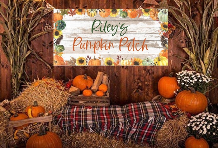 A wooden sign with a white background and a fall theme. The sign has a border of sunflowers, pumpkins, and fall leaves. The text on the sign reads 'Riley's Pumpkin Patch'.