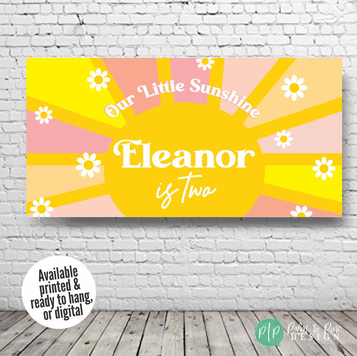 Personalized Our Little Sunshine birthday banner with a cheerful yellow sun, multicolored rays, and daisies, shown against a plain white wall