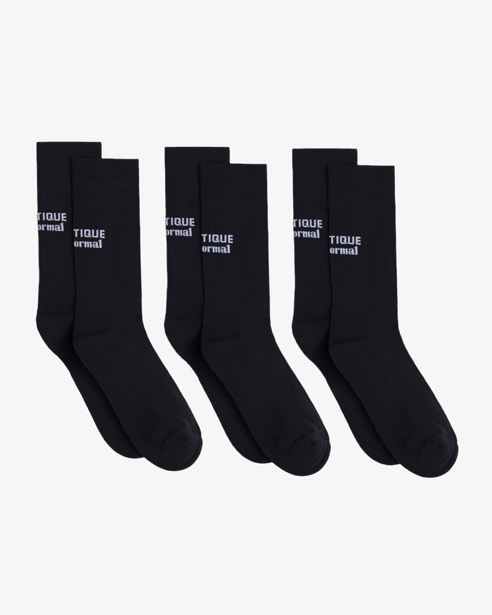 Three pairs of The Athlétique Socks in black, laid flat next to each other on a white background. The image highlights the white c'est normal logo stitched at mid-calf.