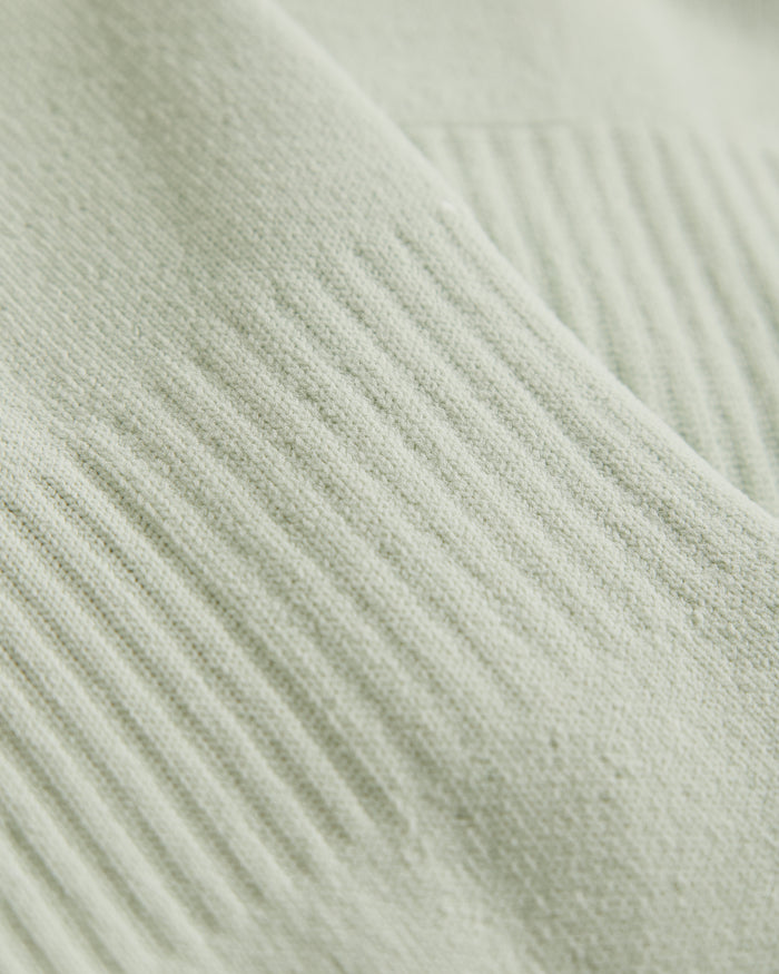A close-up shot of the soft, ribbed cotton fabric of The Athlétique Socks in sage green.