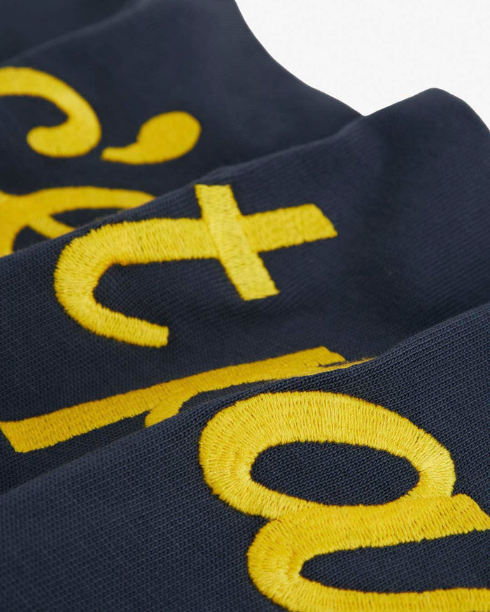 A detailed close-up of The c'est pari Rugby Shirt, focusing on the thick yellow embroidered lettering on the dark fabric.