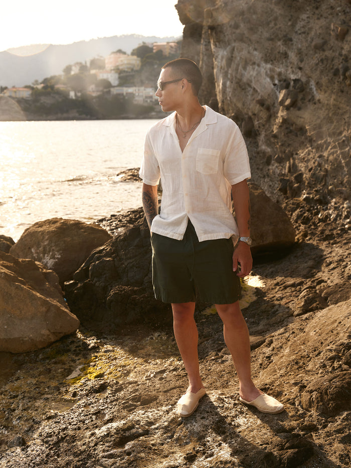 The Holiday Linen SS Shirt in off white — worn on a rocky coast at sunset