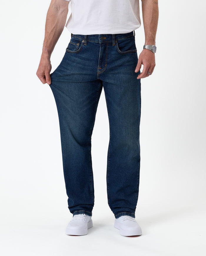 The Jeans Classic Straight Fit in mid wash blue — pulled at the thigh to show fabric stretch