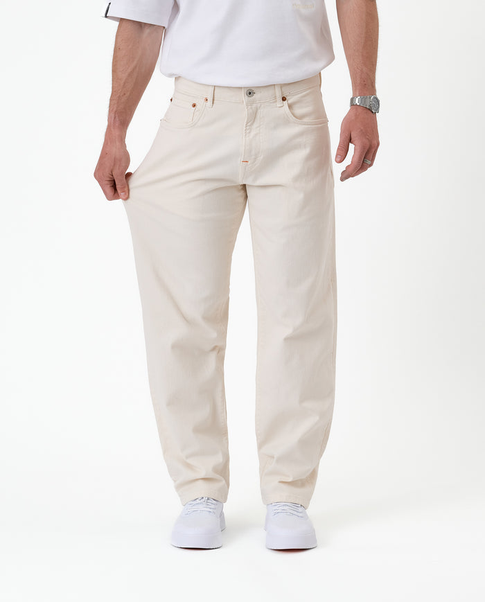 The Jeans Relaxed Straight Fit in ecru — pulling the fabric to demonstrate stretch