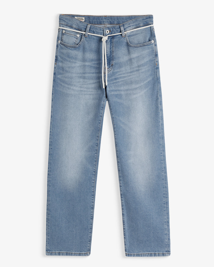 A front view of The Jeans Relaxed Straight Fit in light midwash, laid flat on a white background. The image highlights the front pockets, button closure, and a white drawstring at the waist.