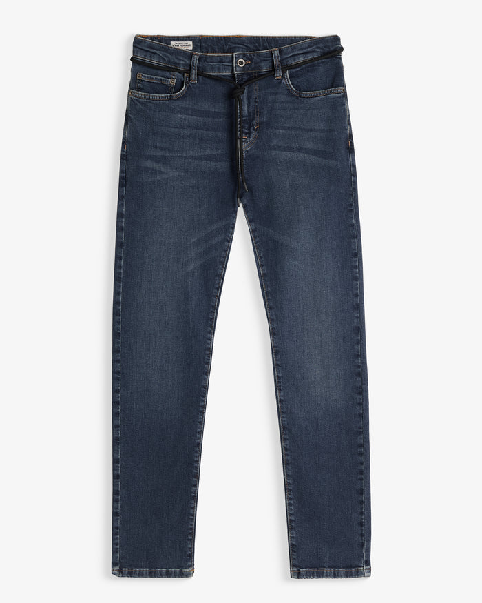 A front view of The Jeans Skinny Fit in midwash, laid flat on a white background. The image highlights the skinny leg cut, classic front pockets, and a black drawstring tie at the waist.