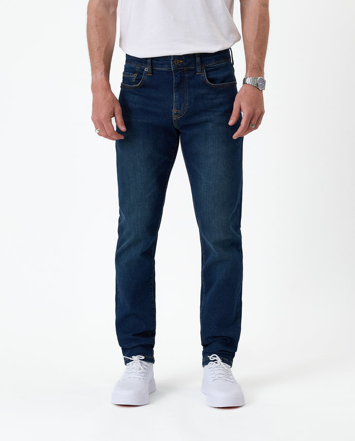 The Jeans Slim Fit in dark blue — front view worn with white sneakers