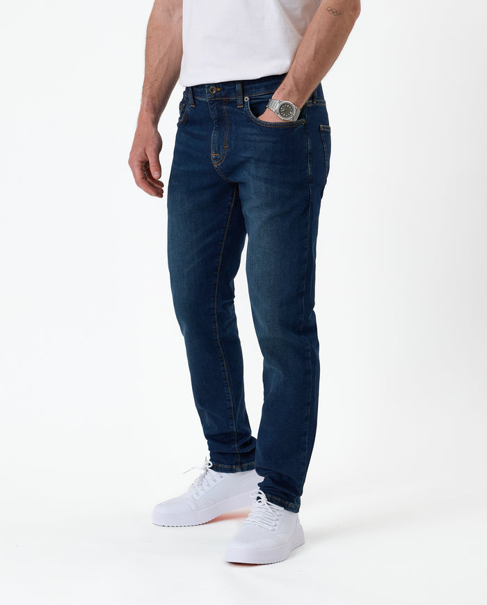 The Jeans Slim Fit in midwash — worn with white sneakers