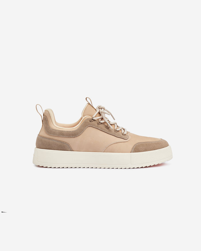 A side view of The Sneakers 2.0 Leather in Sand Leather, laid flat on a white background. The image highlights the tone on tone leather and suede upper, and the white EVA sole.