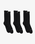 Three pairs of The Sock in black, laid flat on a white background. The image highlights the mid-calf length and the c'est normal logo on the cuff tags and across the toes.