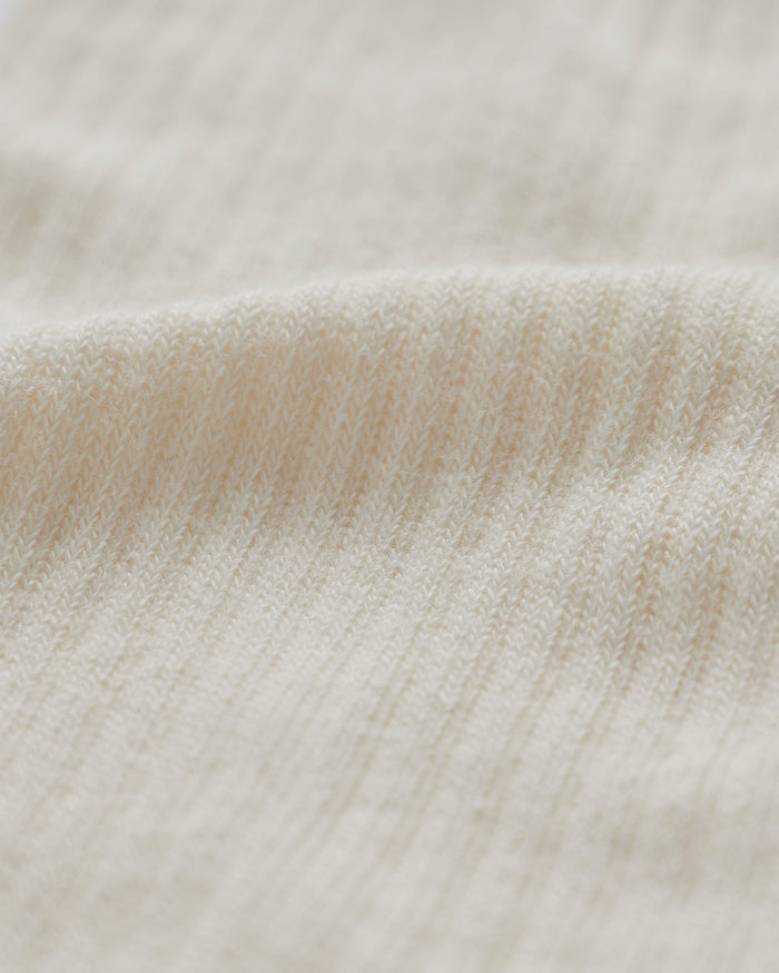 A close-up shot of the soft, ribbed fabric of The Sock in cream, highlighting its knit texture.
