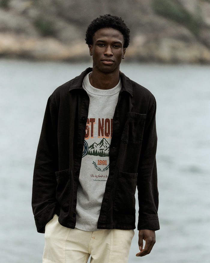 The Workwear Overshirt in black — worn over a C'est normal graphic t-shirt