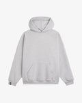 A front view of the Tonal Oversized Hoodie in grey melange, laid flat on a white background. The image highlights the kangaroo pocket, ribbed cuffs and hem, the tone on tone embroidered c'est normal logo on the chest, and the black cuff tag on the right sleeve.