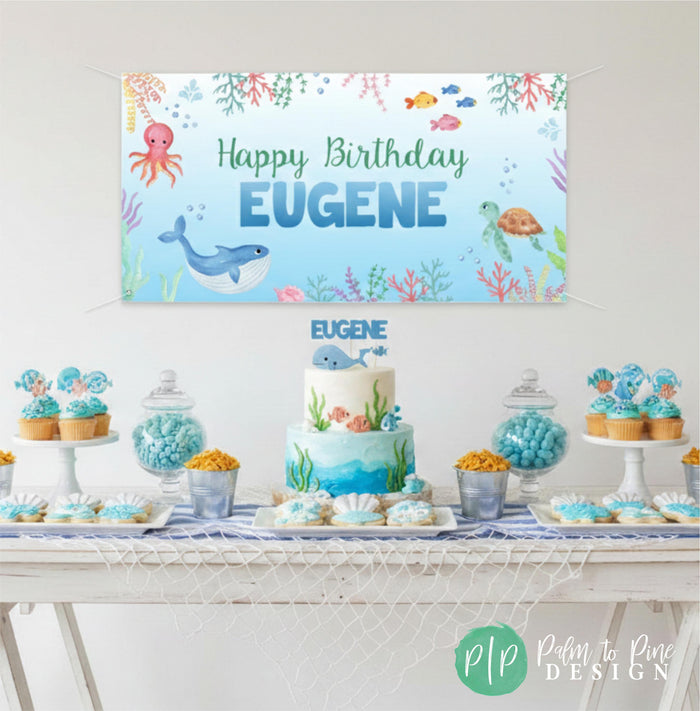 Ocean themed sealife birthday party dessert table with personalized vinyl banner